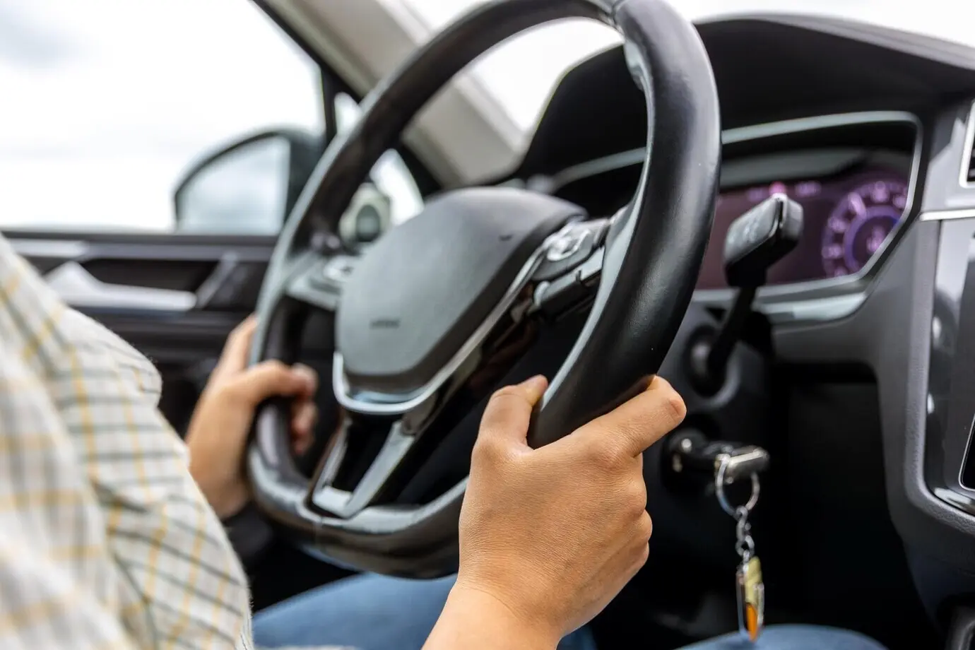 Fahrer am Steuer, Hände am Lenkrad, moderner Fahrzeuginnenraum.